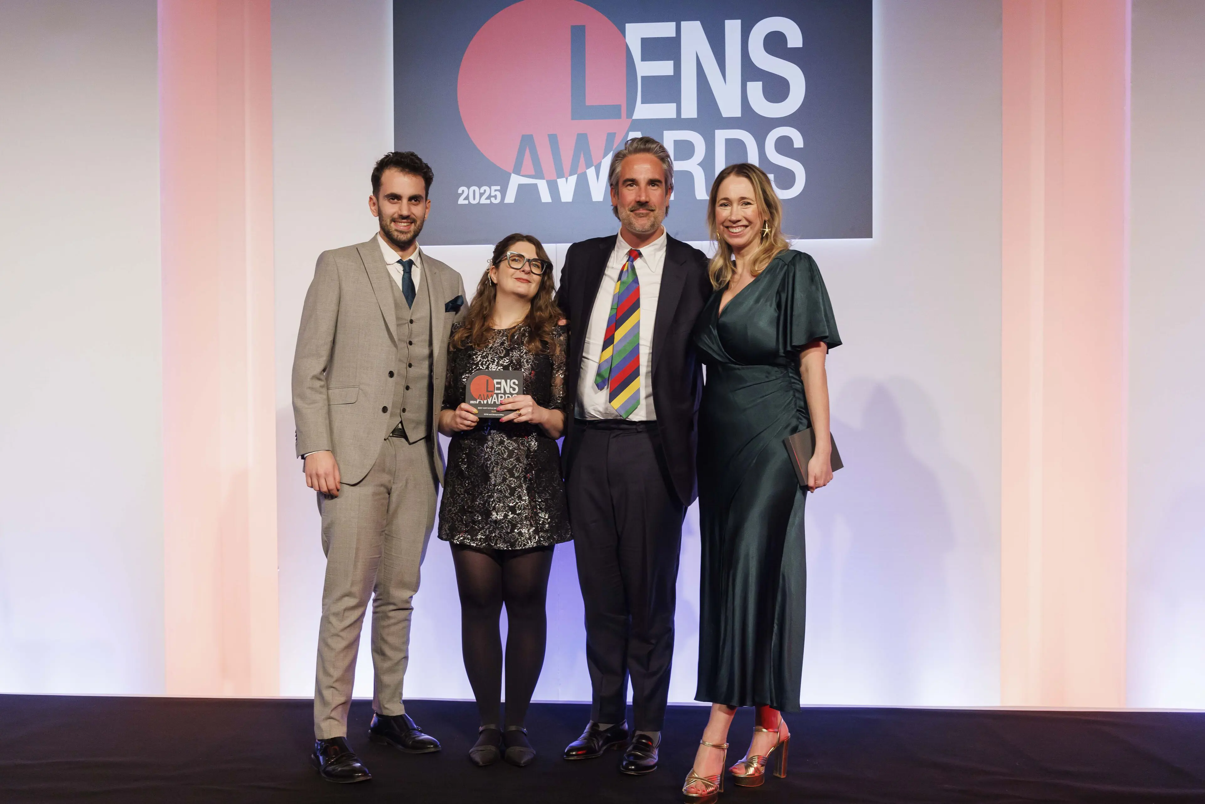 A photo of the some of the SampsonMay team picking up their gold award on stage.